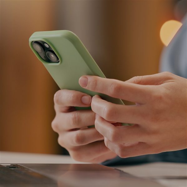 Hands holding a smart phone with a green case.