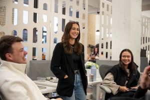Three smiling Curious Plot employees engaging in conversation inside the Curious Plot Minneapolis office.